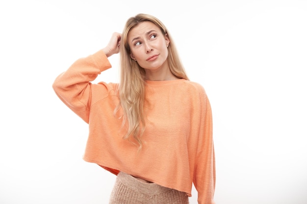 Smart blonde girl in casual holding her head thinks doubts makes decision isolated on white studio background