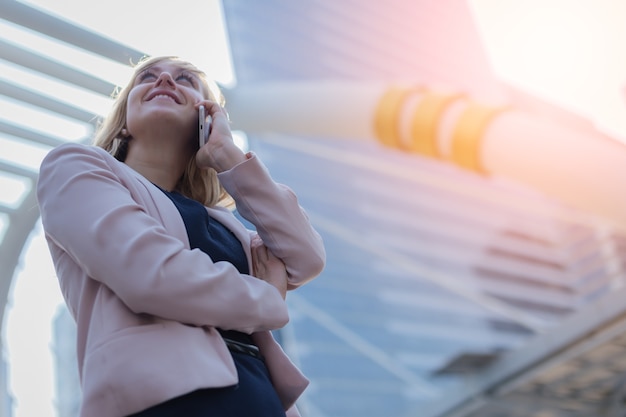 smart caucasian businesswoman hand hold smartphone with blur background of urban city 