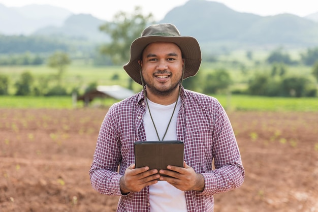 Smart farmer using a technology for studying and development agricultural. The farmer using tablet for tests the growth quality of seedling.