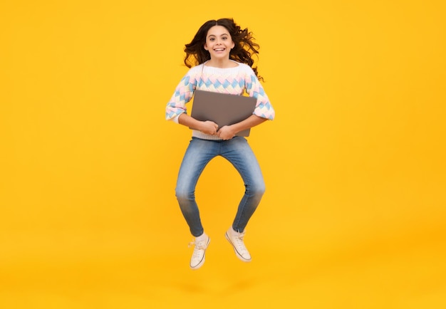 Smart girl with laptop in casual clothes isolated over yellow background Run and jump jumping kids