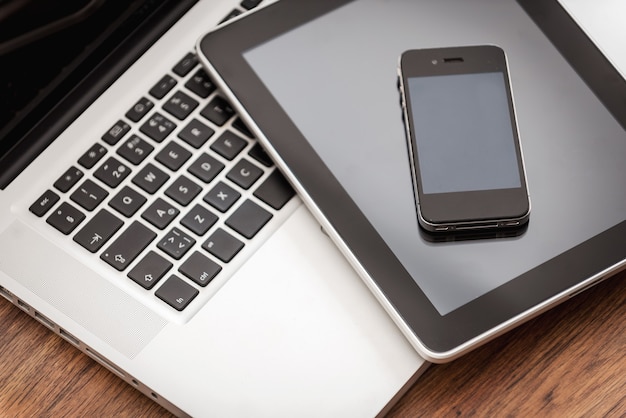 Smart helpers for good business. Close-up of laptop with digital tablet and mobile phone laying on the wooden desk