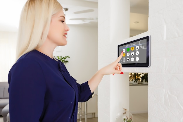 Smart house. Nice joyful woman looking at the sensory panel while pressing it