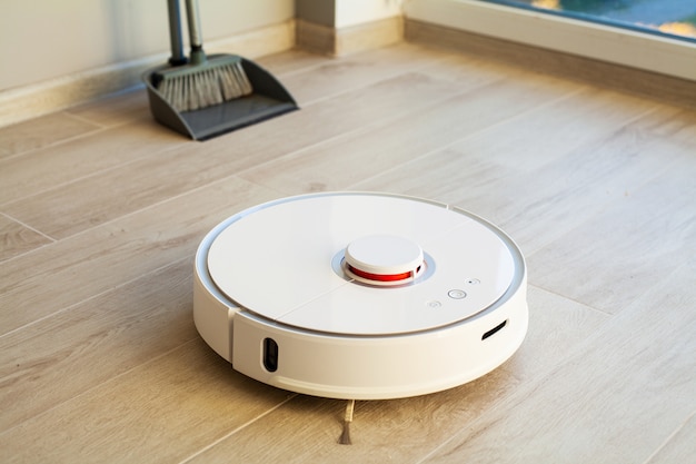 Smart House. Vacuum cleaner robot runs on wood floor in a living room