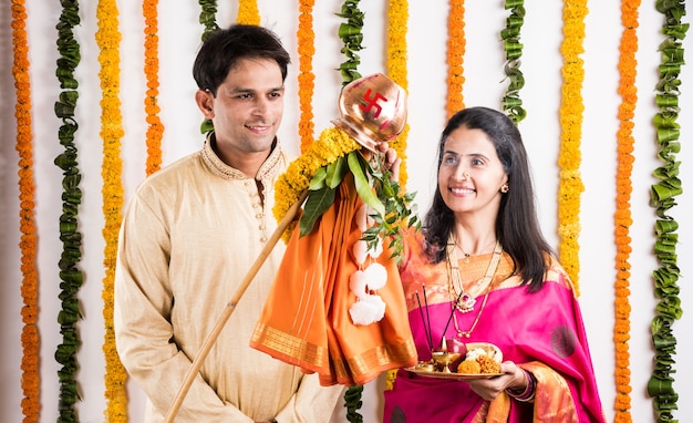 Smart Indian young couple performing Gudi Padwa Puja in traditional cloths & pooja thali. It's a Hindu New Year celebrated across India