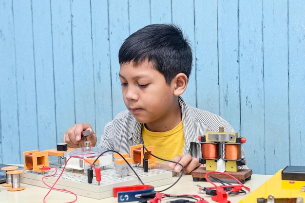 Smart looking Asian boy working with circuits, wires, computer, motor on his project. Science, Techn