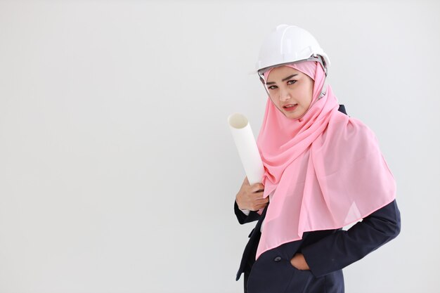 Smart muslim young asian woman wearing blue suit smiling confident holding blueprint in studio