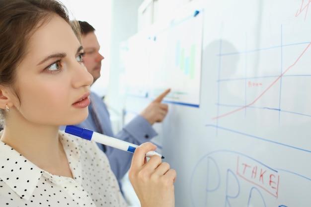 Smart pensive woman draw graphics and charts on white board