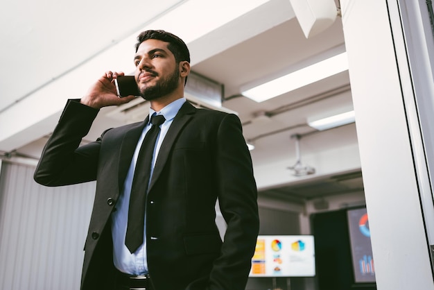 Smart and positive businessman calling and talking on smartphone alone in the office Professional making business calls on the phone and enjoying corporate mobile conversation indoors