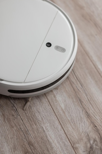 Smart robot vacuum cleaner cleans the house on a wooden floor Cleaning every day Helper