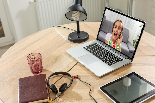 Smart small preschooler girl watch online lesson and communicate with teacher at home, little child study on Internet using laptop wireless connection.