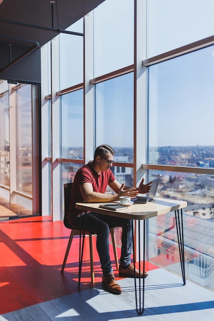 Smart software developer sitting at desktop in coworking space with laptop and creating publishing idea using netbook for messaging and networking during freelance work