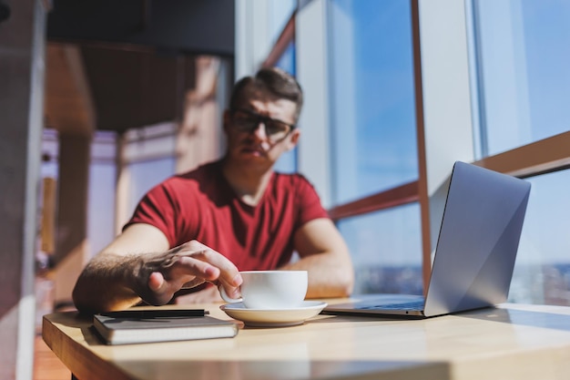 Smart software developer sitting at desktop in coworking space with laptop and creating publishing idea using netbook for messaging and networking during freelance work