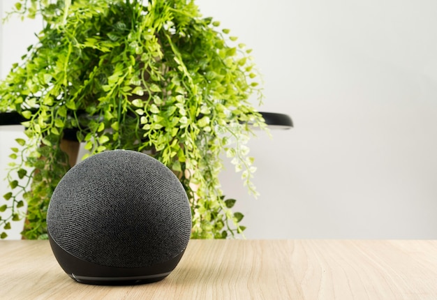 Smart speaker and a virtual assistant. It is used to keep the home connected and give orders by voice to other electronic devices. Modern technology. Wooden background.