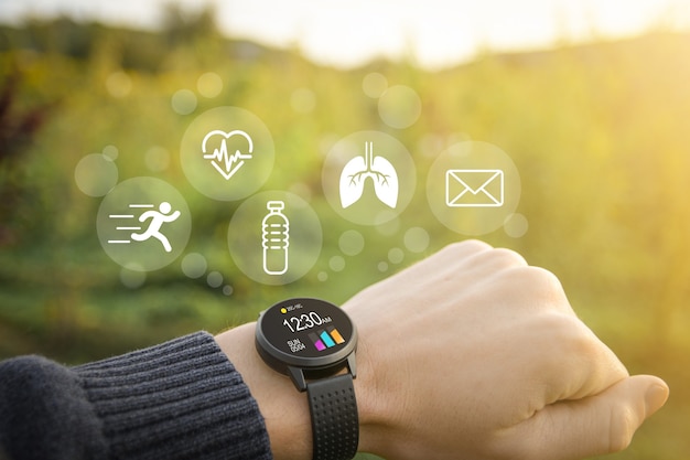 Smart watch, fitness tracker on hand in the outdoor on a blurred green