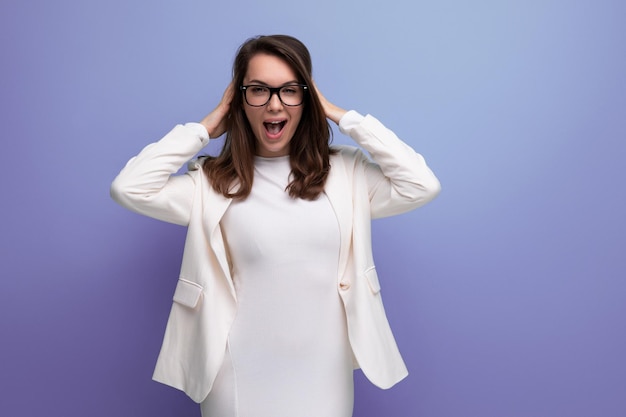 Smart woman with thick dark hair in white outfit on studio background