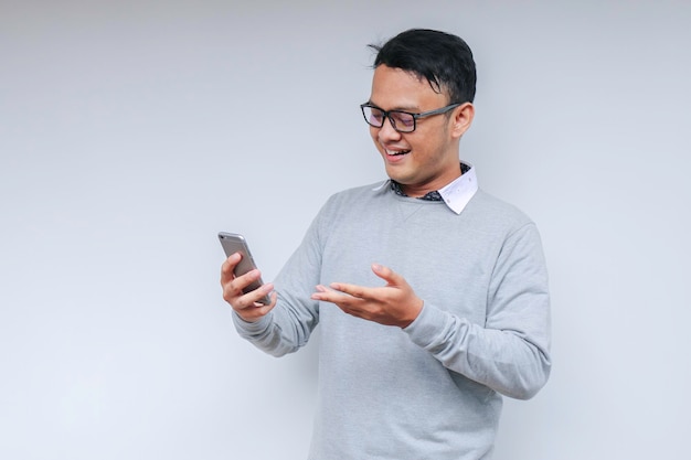 Smart Young asian man is happy and smiling when using smartphone in studio background