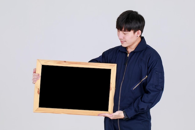 Smart young chinese guy on service uniform jacket holding square wooden blackboard with smile