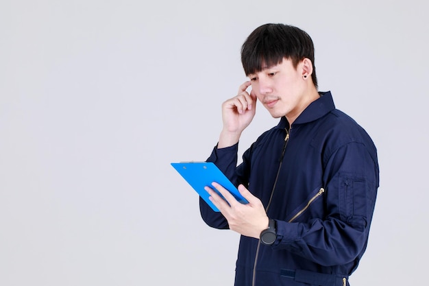 Smart young chinese guy on service uniform jacket recording creative idea by writing memo on note board and consider future design and vision by thinking about strategy to aim target as planning.