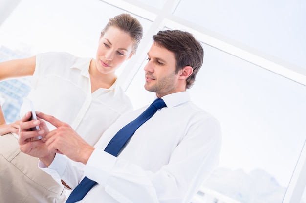 Smartly dressed colleagues looking at mobile phone