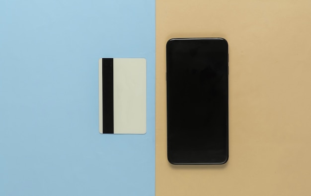 Smartphone and bank card on pastel background. Contactless payment. Online shopping. Top view. Minimalism