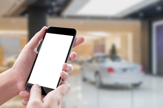 Smartphone blank screen in woman hands over blurred background at Showroom.