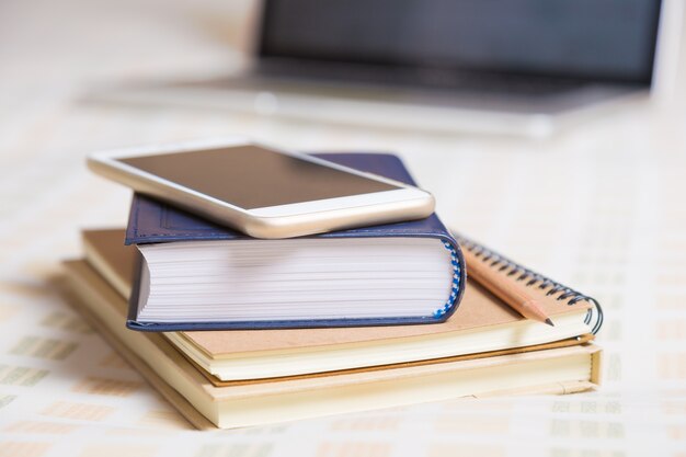 Smartphone, books, pencil, computer, all on bed