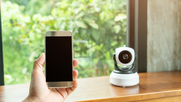 Smartphone connecting with security IP camera on a wooden table.