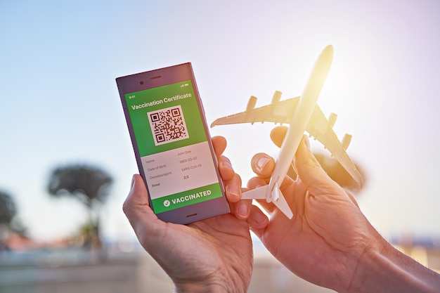 Smartphone displaying on app mobile valid digital green vaccination certificate for Covid19 and airplane toy in hand