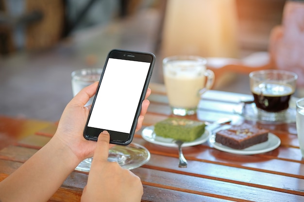 Smartphone in hand with coffee and cake on table