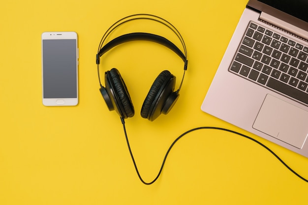 Smartphone, headphones and a laptop on yellow 