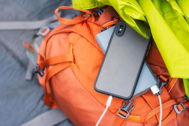 The smartphone is being charged with a portable charger Power bank with a mobile phone on a sleeping bag with a backpack