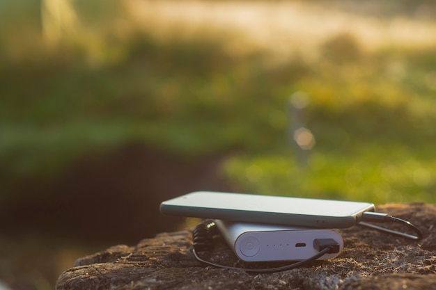 Smartphone is charged using a portable charger. Power Bank charges the phone outdoors with a backpack for tourism in nature.