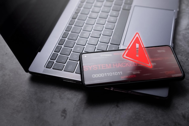 Photo smartphone laying on laptop with red warning notification system warning hacked alert