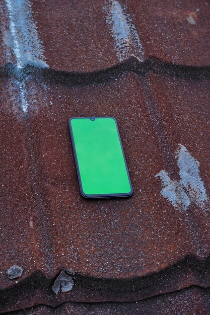 A smartphone mockup featuring a vibrant green screen that stands out against a rich brown background