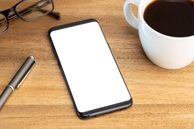 Smartphone mockup template with coffee cup and eyeglasses on wooden table White screen