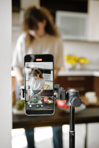 Photo smartphone recording a focused woman preparing food in a modern kitchen