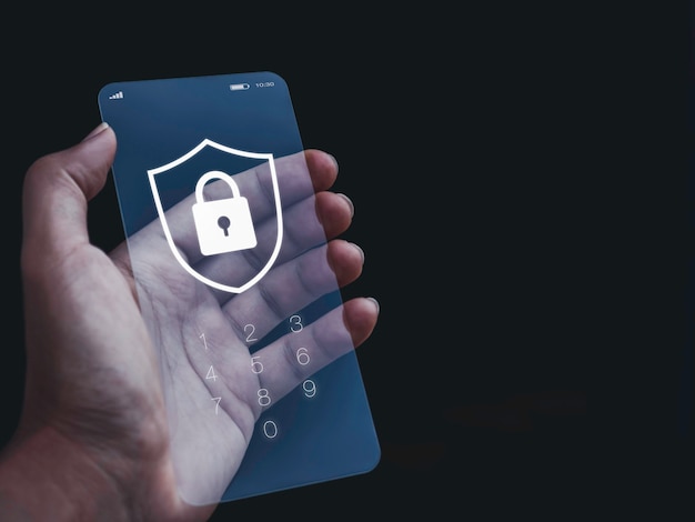 Smartphone security and privacy concept. White shield and lock icon graphic with numbers for password on lock screen of futuristic transparent glass phone in hand on dark background with copy space.