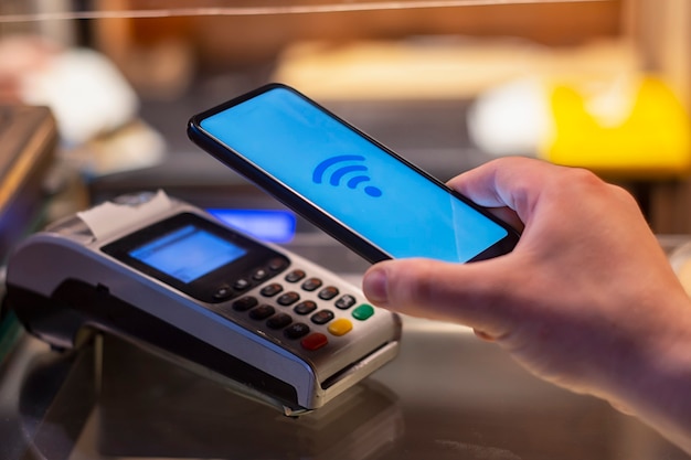 Smartphone in shop using NFC technology against the background of the payment terminal.