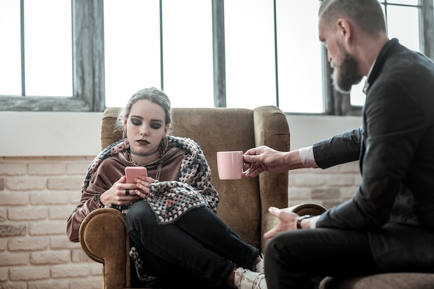 Smartphone not talk. Teenage girl using her smartphone instead of talking to professional psychologist