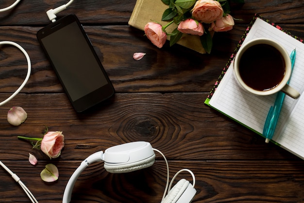 Smartphone with headphones and coffee cup on the table