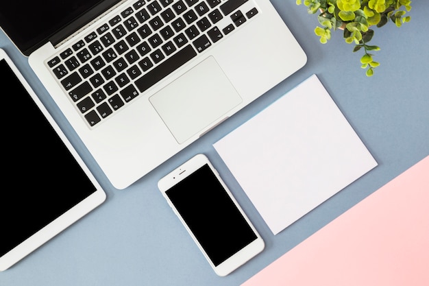 Smartphone with laptop and blank paper on table