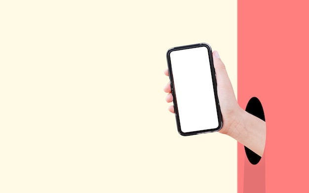 Smartphone with mockup in hand from hole against two walls of pastel red and yellow colors.