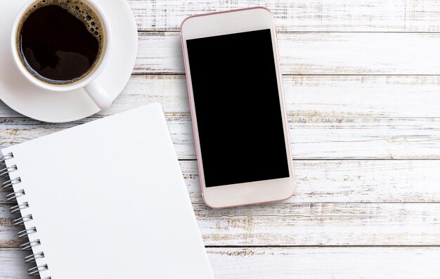 Smartphone with notebook and cup of coffee