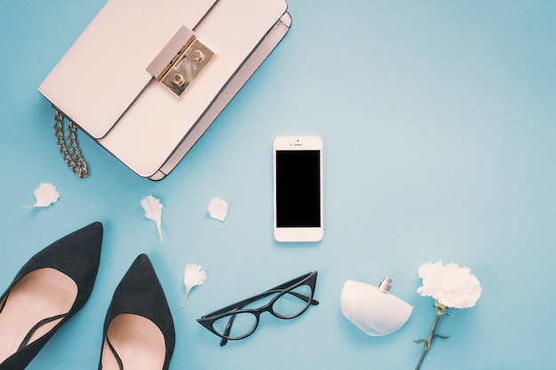 Smartphone with woman shoes and flower on table