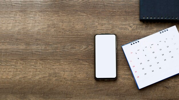 Smartphonecalender on old woodle background top view mockup screen