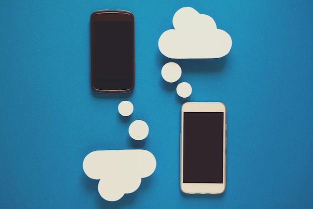 Smartphones with paper speech bubbles on blue background Communication concept