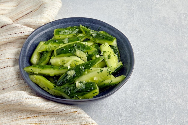 Smashed lightly salted broken cucumbers in a ceramic bowl surrounded by dill