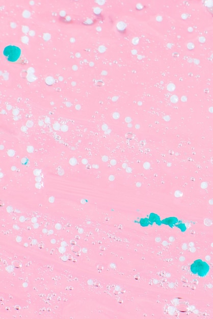 Smeared transparent gel with blue granules On a pink background