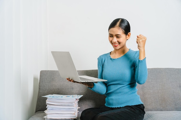 Smile asian business woman using laptop while sitting on couch at home