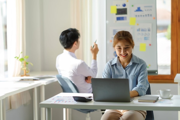 Smile Asian businesswoman sitting working on laptop in office